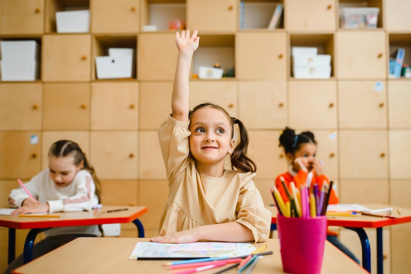 Girl raising hand in classroom during a WTW spelling activity